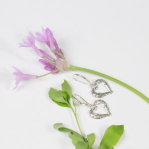 A pair of earrings and a flower on a table.