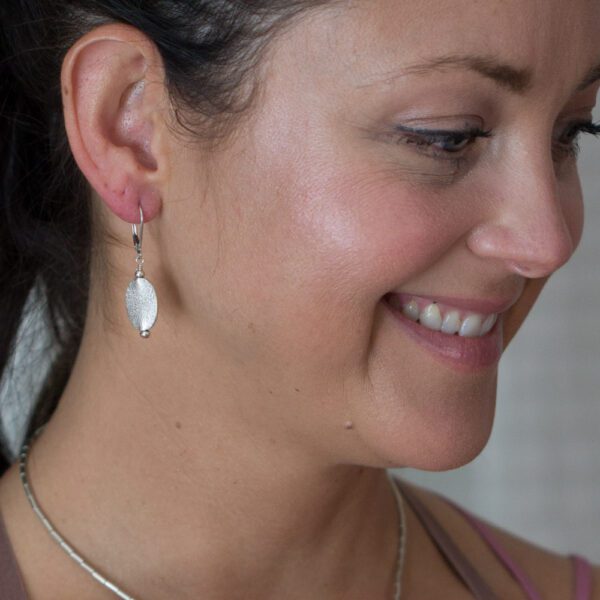 A woman wearing earrings and smiling.