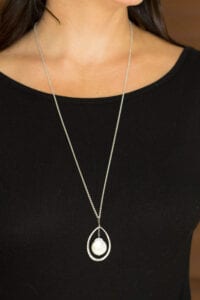 A woman wearing a necklace with a pearl in it.