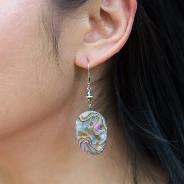 A woman wearing earrings with colorful designs on them.