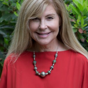 A woman in red shirt wearing necklace and smiling.