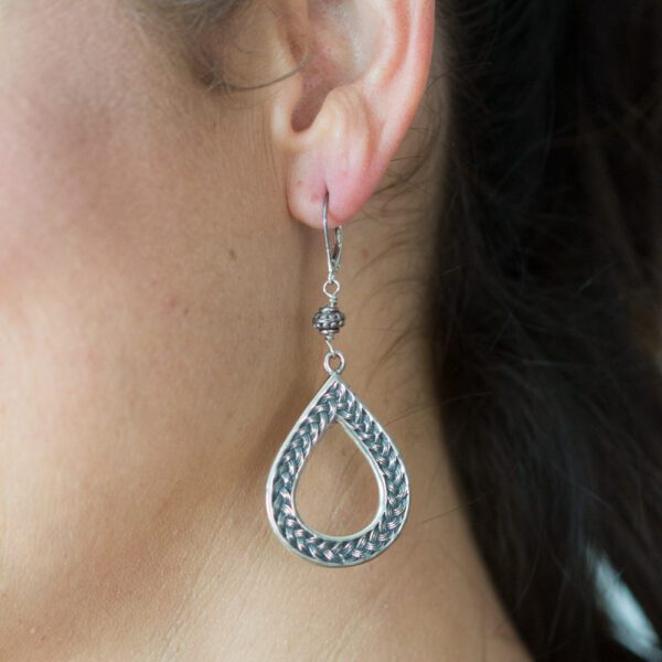 A woman wearing silver earrings with chain design.