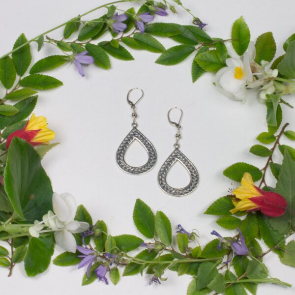 A pair of earrings sitting in the middle of some flowers.