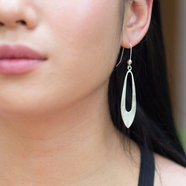 A woman wearing earrings with long dangling oval shapes.