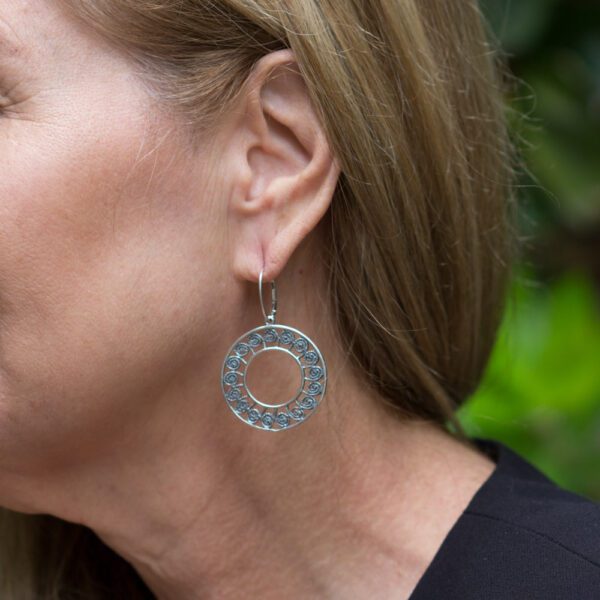 A woman wearing silver earrings with floral designs.