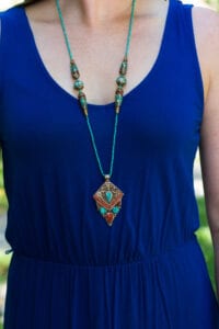 A woman wearing a blue dress and necklace.