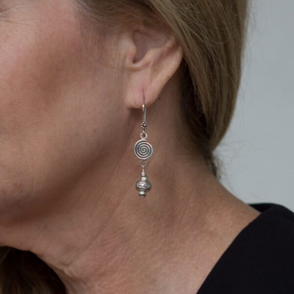 A woman wearing silver earrings with a black shirt.