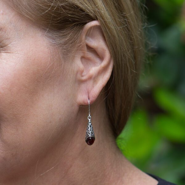 A woman wearing earrings with a black stone.