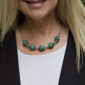 A woman wearing a necklace with green beads.