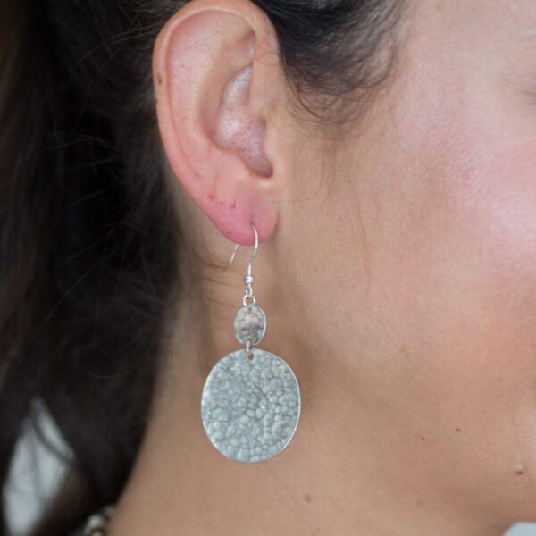 A woman wearing silver earrings with a star on it.