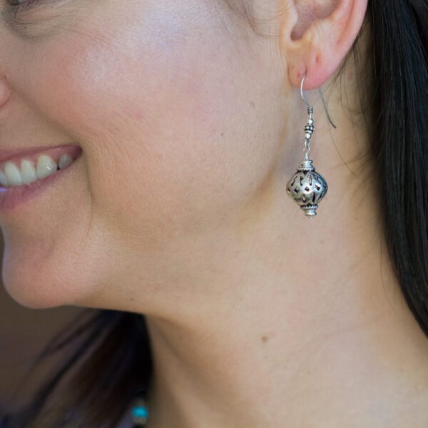 A woman wearing earrings with a smile on her face.