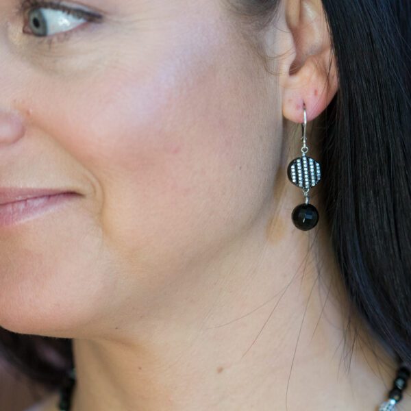 A woman wearing earrings with black beads.