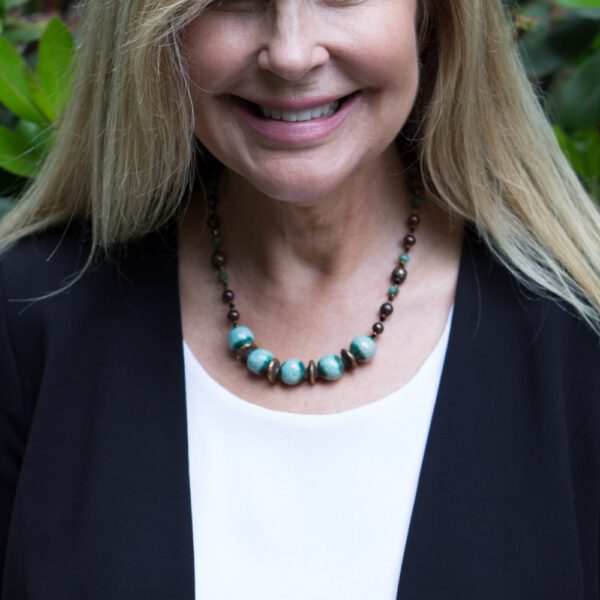 A woman wearing a necklace and smiling for the camera.