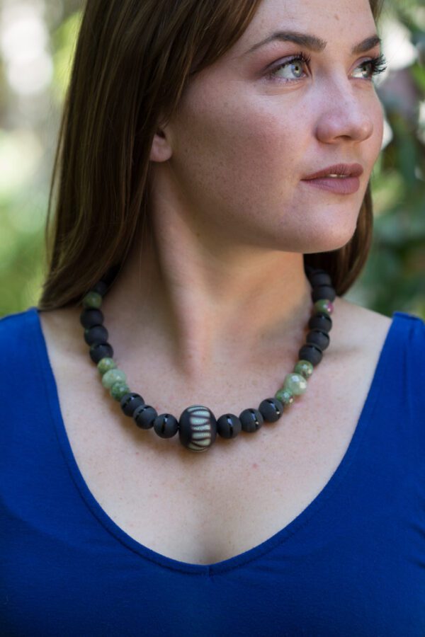 A woman wearing a necklace with green and black beads.