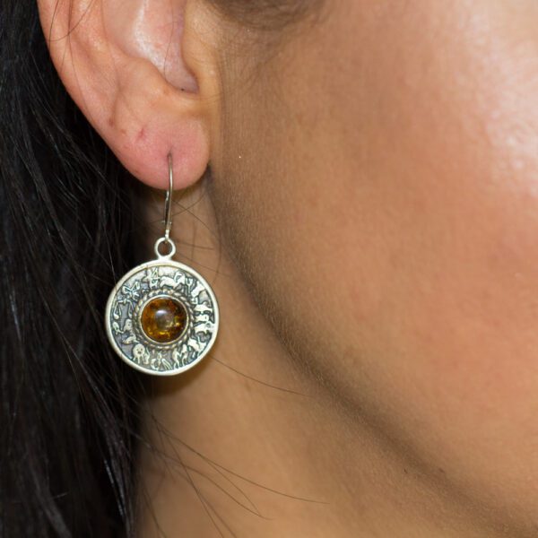 A woman wearing earrings with an image of a bullet shell.