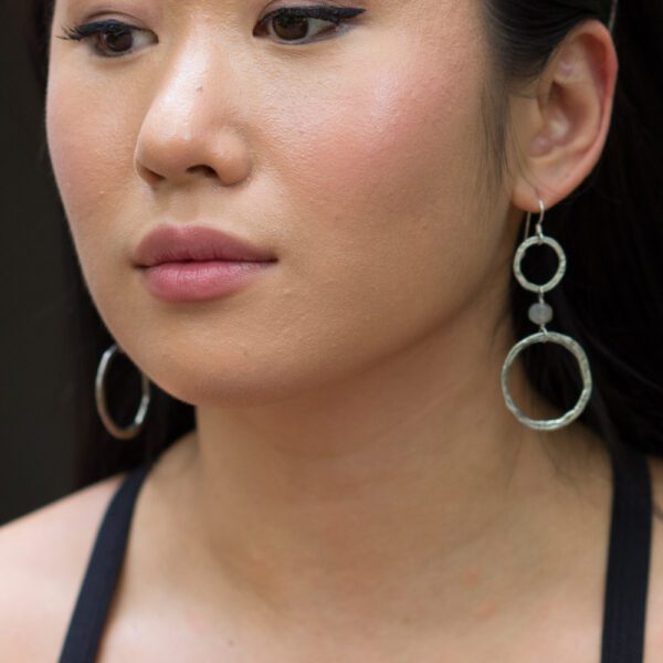 A woman with long black hair wearing large silver earrings.