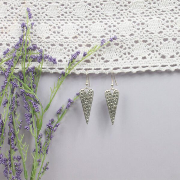 A pair of earrings hanging on the wall next to lavender.