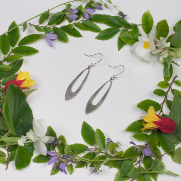 A pair of silver earrings sitting in the middle of a floral wreath.