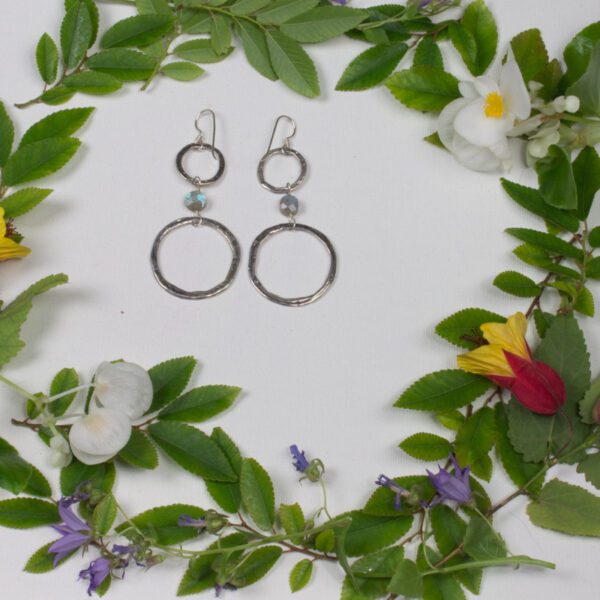 A pair of earrings sitting in the middle of some flowers.