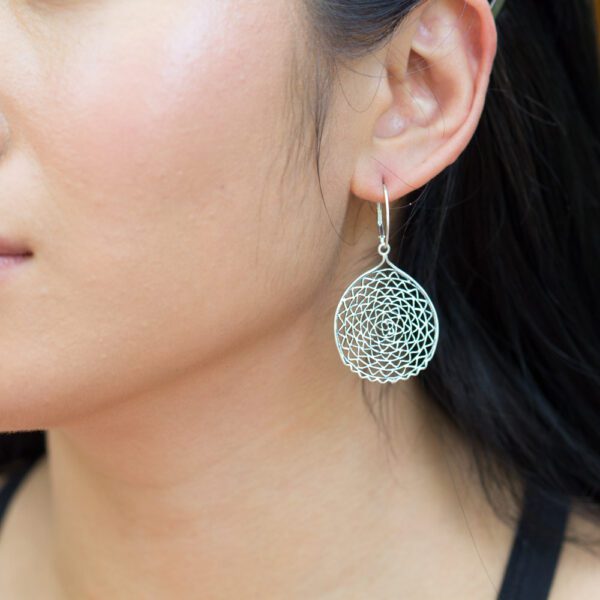 A woman wearing earrings with a flower design.