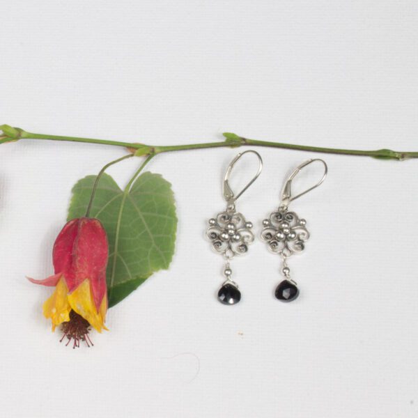 A pair of earrings sitting on top of a flower.