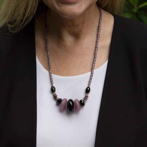 A woman wearing a necklace with black and pink beads.