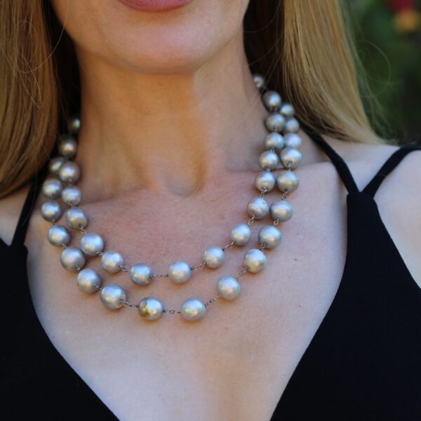 A woman wearing a two strand necklace of grey pearls.