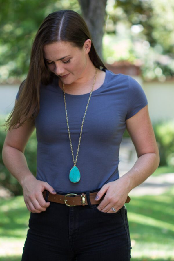 A woman wearing a blue shirt and brown belt