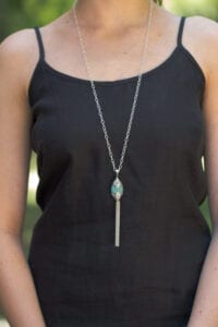 A woman wearing a black top and necklace.