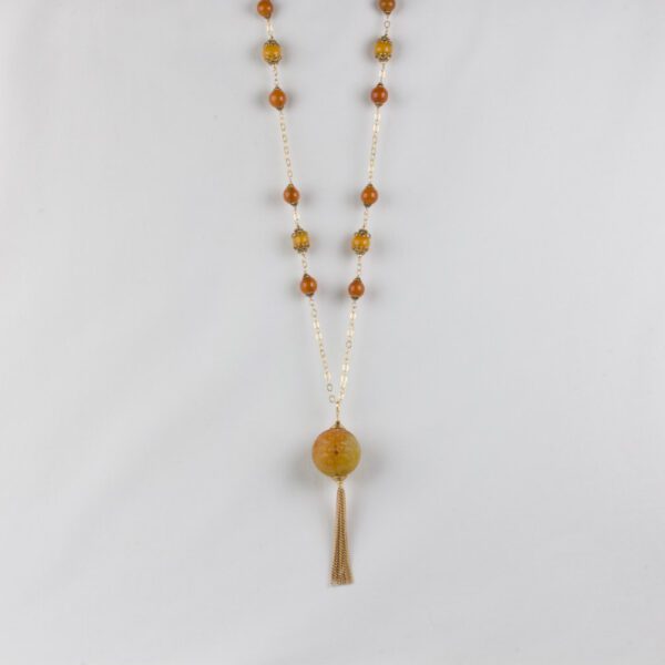 A long necklace with an orange bead and tassel.