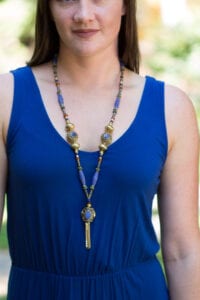 A woman wearing a blue top and necklace.