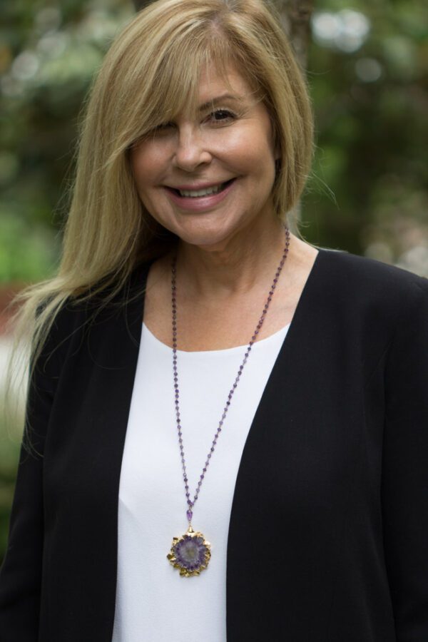 A woman with long blonde hair wearing a black jacket.