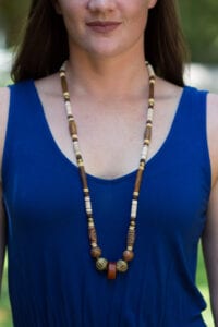 A woman wearing a blue top and necklace.