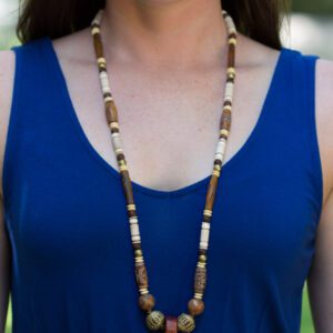 A woman wearing a blue top and necklace.