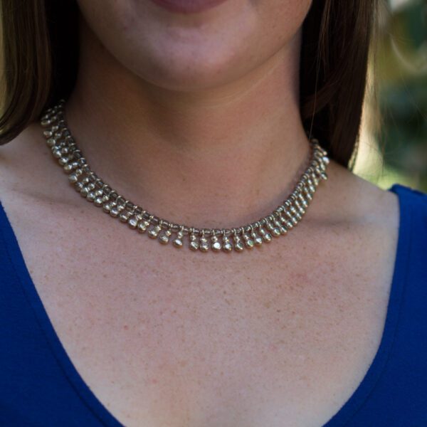 A woman wearing a necklace with gold chain.