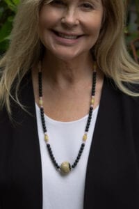 A woman wearing a necklace with black and gold beads.