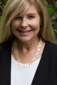 A woman wearing a necklace and smiling for the camera.