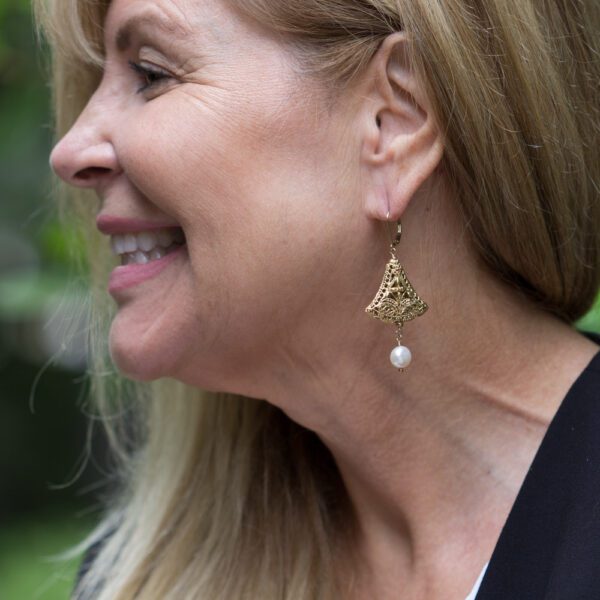 A woman with long blonde hair wearing gold earrings.