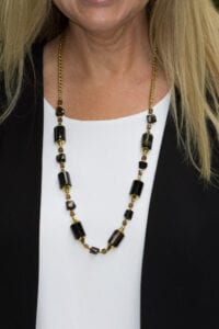 A woman wearing a black and gold necklace.