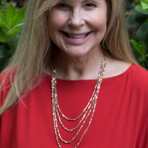 A woman wearing a red top and gold necklace.