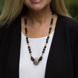 A woman wearing a necklace with black and gold beads.