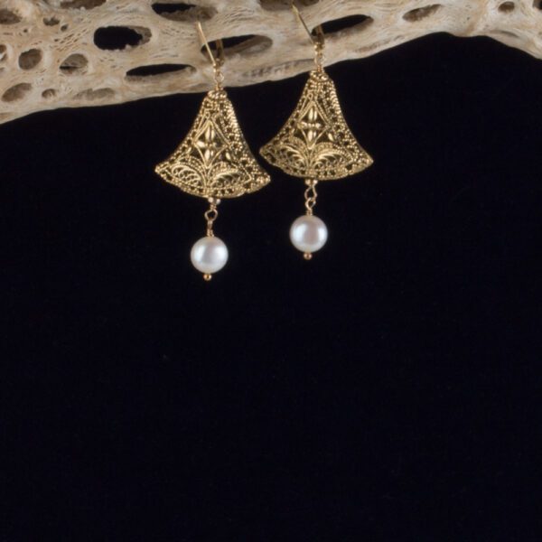 A pair of gold earrings hanging from a piece of wood.