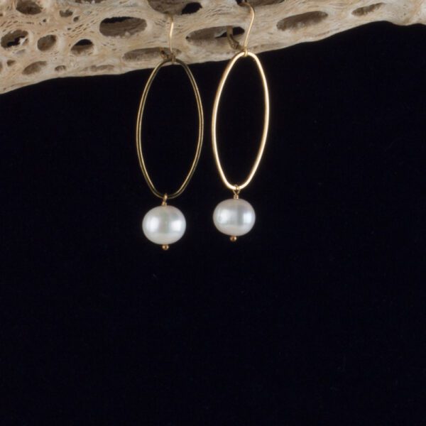 A pair of gold hoop earrings with pearls hanging from them.