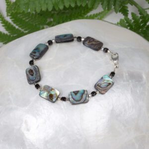 A bracelet with rectangle abalone shell, small sterling silver and black beads.