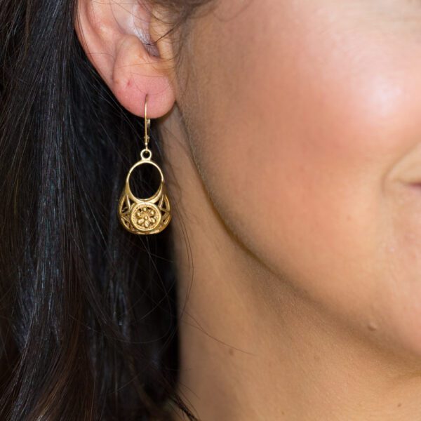 A woman wearing gold earrings with a black background