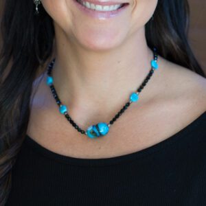 A woman wearing a necklace with blue beads.