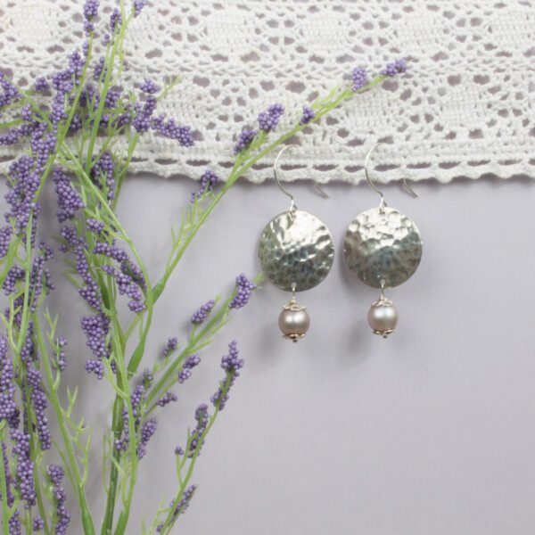 A pair of earrings with a flower on the side.