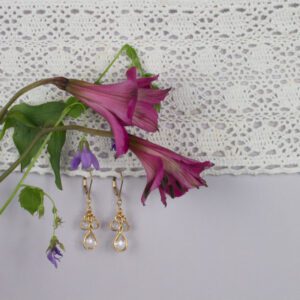 A pair of earrings hanging on the wall next to flowers.