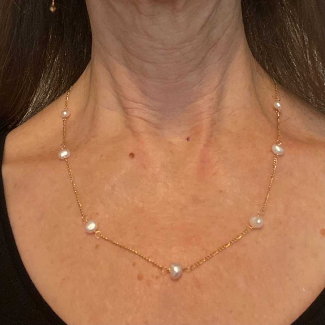 A woman wearing a necklace with pearls on it.