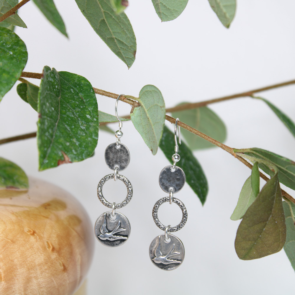 3 sterling silver rings graduating in size, bottom disk image of a bird.